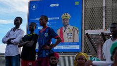 People stand in front of a billboard showing Guinea's General Mamadi Doumbouya, ahead of a constitutional referendum in Conakry, Guinea [File: Misper Apawu/AP]