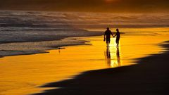 Couple taking a romantic walk on the beach at Sunset