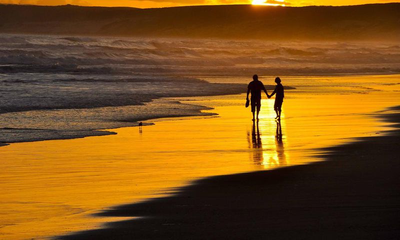 Couple taking a romantic walk on the beach at Sunset