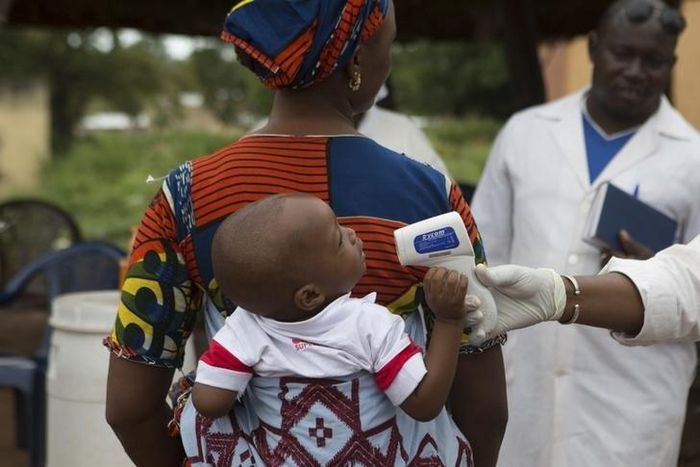 A health worker checks the temperature of a baby entering Mali from Guinea at the border in Kouremale, October 2, 2014.   REUTERS/Joe Penney