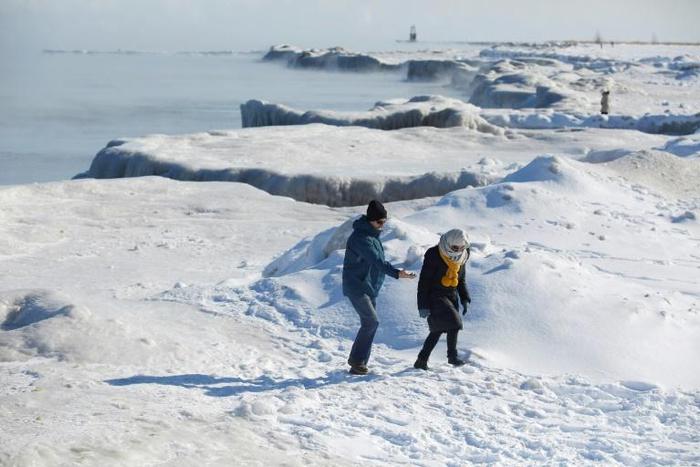 People walk along Lake Michigan's frozen shoreline as temperatures dropped to -20 degrees F (-29C) Chicago