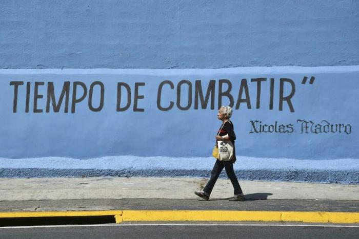 A woman passes graffiti with a partial phrase attributed to Venezuelan President Nicolas Maduro reading "Time to Fight", in Caracas, ahead of competing protests by opposition supporters and regime loyalists