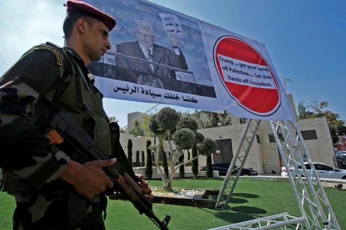 A member of the Palestinian security forces stands in front of a poster of President Mahmud Abbas, during a protest in Bethlehem on September 26, 2018 against Washington's decision to cut aid