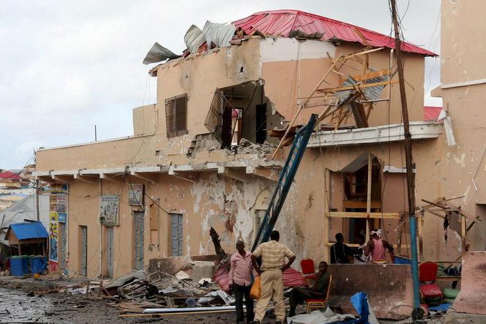 People stand near debris at the scene of an explosion at the gate of Siyad hotel after Friday night's attack in Somalia's capital Mogadishu, July 11, 2015. REUTERS/Feisal Omar TPX IMAGES OF THE DAY