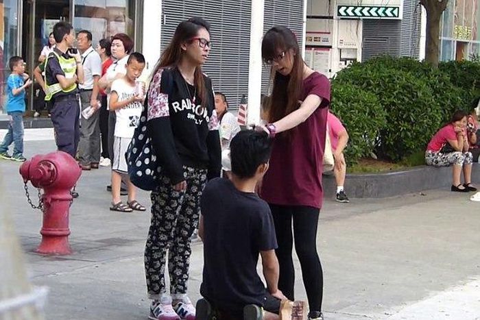 A Chinese woman has been arrested after forcing her boyfriend to kneel in the street and repeatedly slapping him around the face.