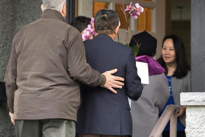 (FILES) In this file photo taken on December 12, 2018 Meng Wanzhou (R), Chief Financial Officer of Huawei Technologies, answers the door for individuals carrying flowers after she was released on bail in Vancouver, British Columbia on December 12, 2018...