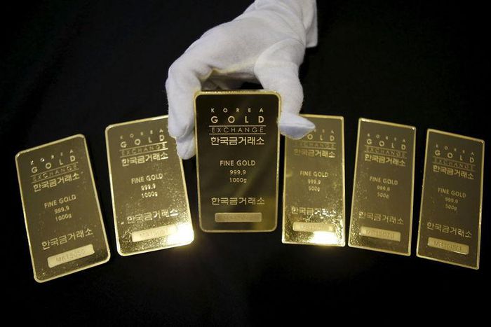 An employee poses for photographs with gold bars at the Korea Gold Exchange in Seoul, South Korea, July 31, 2015. REUTERS/Kim Hong-Ji/Files