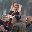 Supporters of the Muslim Brotherhood and ousted Egyptian President Mohamed Mursi hold a copy of the Koran and Mursi's picture at Talaat Harb Square, in Cairo, January 25, 2015. REUTERS/Mohamed Abd El Ghany