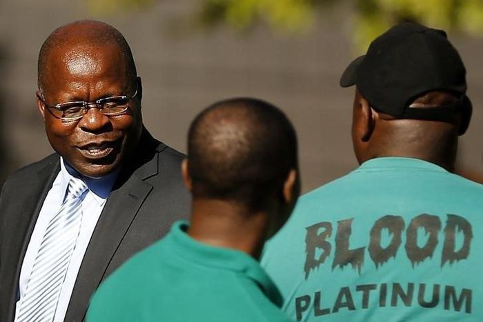 Lonmin Chief Executive Ben Magara (L) looks on after accepting a memorandum from striking miners outside Lonmin's headquarters in Johannesburg, April 3, 2014. REUTERS/Siphiwe Sibeko