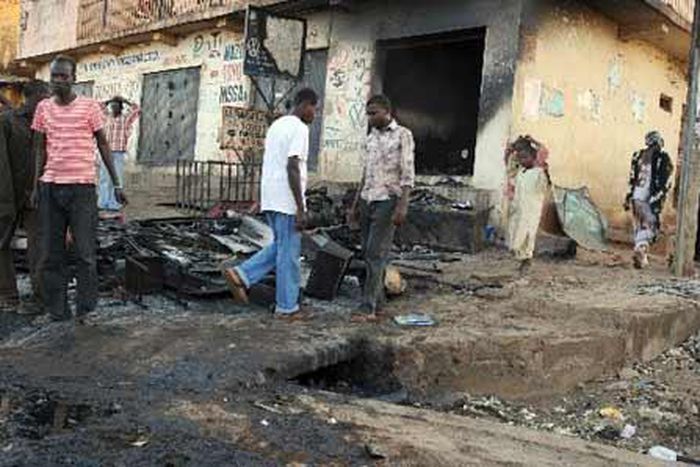 People walk past a burnt house in Nigeria's central Plateau State's capital Jos, November 30, 2008