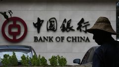 A man is silhouetted in front of a Bank of China's logo at its branch office in Beijing July 14, 2014.   REUTERS/Kim Kyung-Hoon
