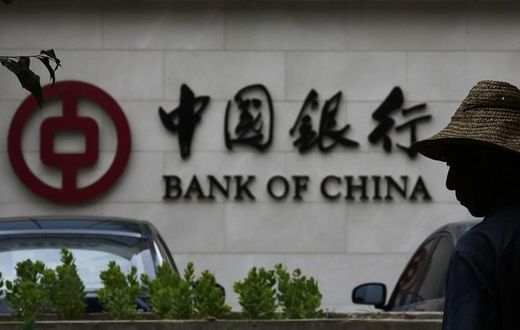 A man is silhouetted in front of a Bank of China's logo at its branch office in Beijing July 14, 2014.   REUTERS/Kim Kyung-Hoon