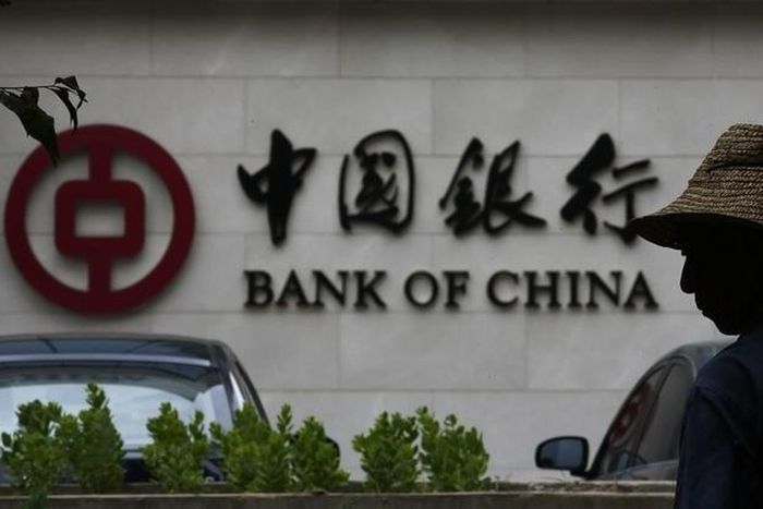 A man is silhouetted in front of a Bank of China's logo at its branch office in Beijing July 14, 2014.   REUTERS/Kim Kyung-Hoon