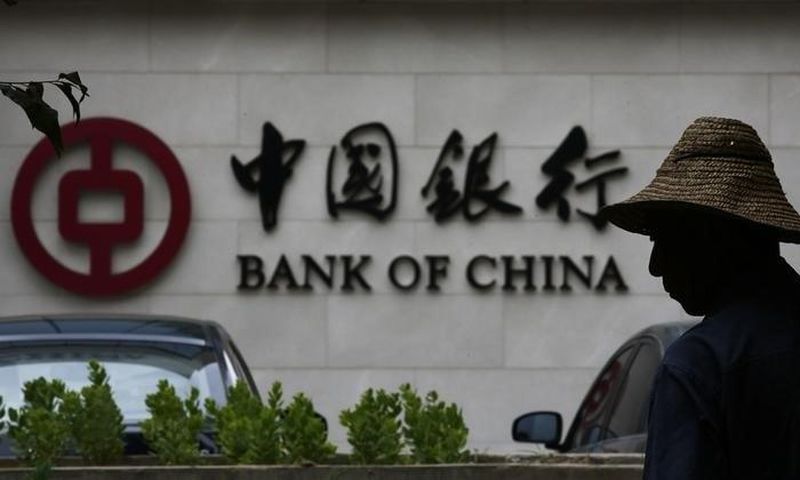 A man is silhouetted in front of a Bank of China's logo at its branch office in Beijing July 14, 2014.   REUTERS/Kim Kyung-Hoon
