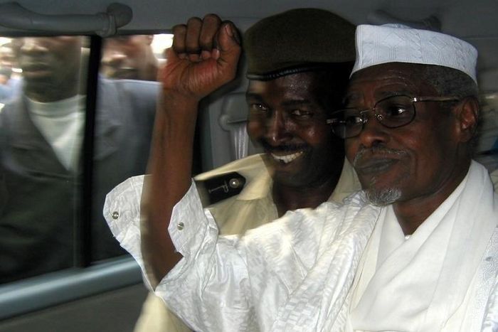 Former Chad President Hissene Habre (R) raises his fist in the air as he leaves a court in Dakar escorted by a Senegalese policeman November 25, 2005,  file photo.   REUTERS/Aliou Mbaye