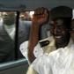 Former Chad President Hissene Habre (R) raises his fist in the air as he leaves a court in Dakar escorted by a Senegalese policeman November 25, 2005,  file photo.   REUTERS/Aliou Mbaye