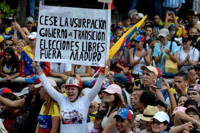 A woman holds a poster demanding free elections during an opposition rally against leader Nicolas Maduro
