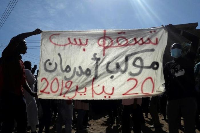 Sudanese demonstrators hold up a banner bearing a slogan calling for the overthrow of the regime during an anti-government protest in Khartoum's twin city Omdurman on January 20, 2019