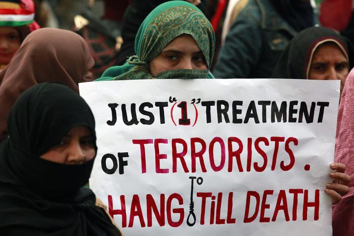 A supporter of political party Pakistan Awami Tehreek (PAT), holds a sign with others to condemn the attack by Taliban gunmen on the Army Public School in Peshawar, during a rally in Lahore December 21, 2014.