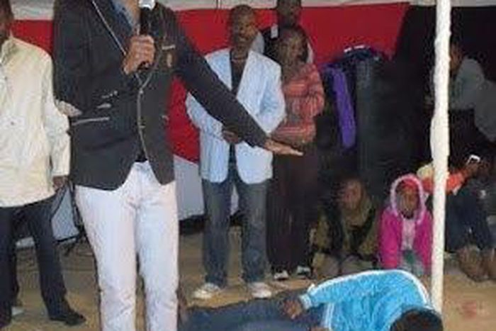 South African Pastor during prayers with the young man on the floor