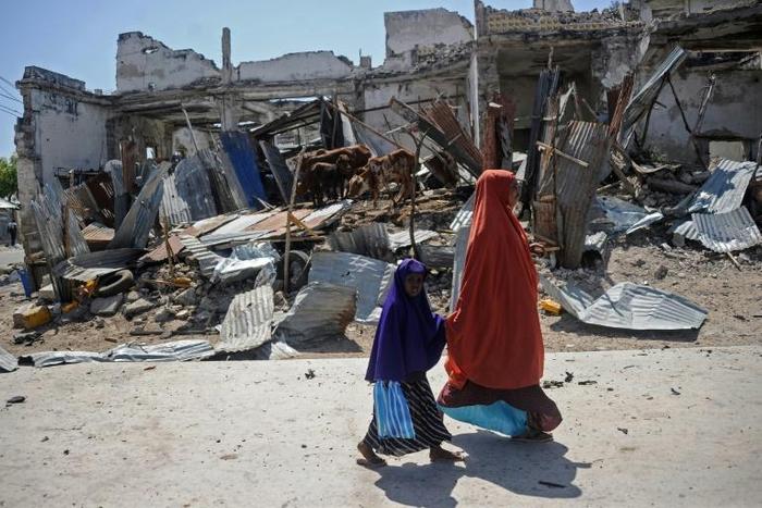 Local residents walk past the scene of a deadly December 22, 2018 car bomb attack in the Somali capital Mogadishu claimed by the jihadist group Shabaab