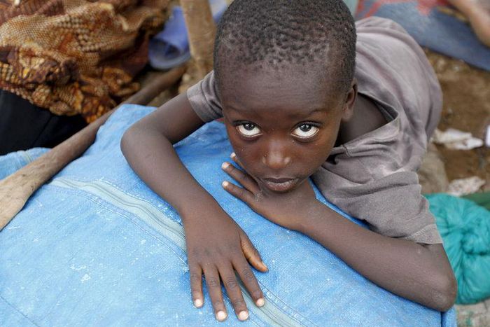 A Burundian refugee child rests on their belongings on the shores of Lake Tanganyika in Kagunga village in Kigoma region in western Tanzania, as they wait for MV Liemba to transport them to Kigoma township, May 18, 2015. REUTERS/Thomas Mukoya