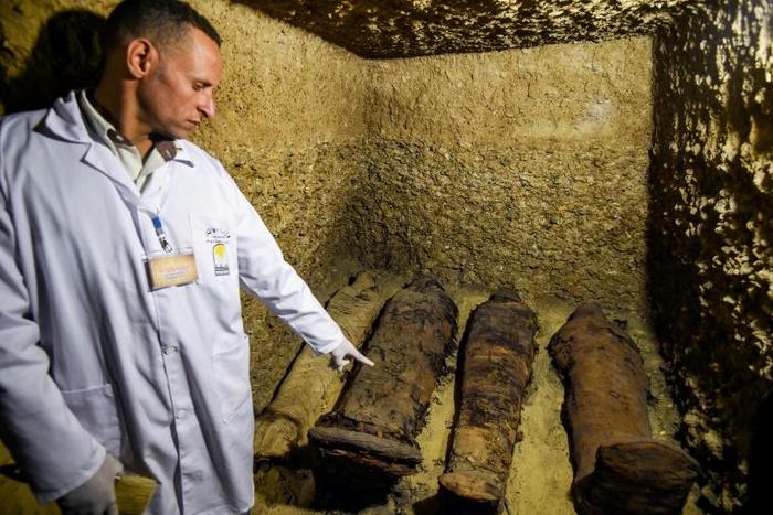 An archaeologist displays mummies laying in burial chambers dating to the Ptolemaic era (323-30 BC), in Egypt's Minya province on February 2, 2019