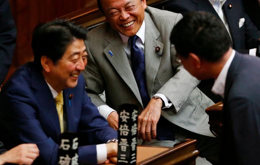 Financial Minister Taro Aso, center, and Japanese Prime Minister Shinzo Abe, left, share a light moment during a plenary session at the lower house in Tokyo, Thursday, July 16, 2015.