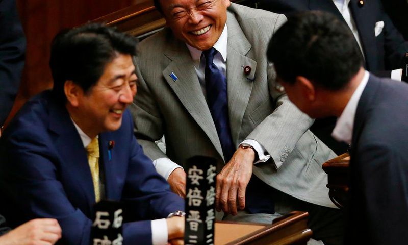 Financial Minister Taro Aso, center, and Japanese Prime Minister Shinzo Abe, left, share a light moment during a plenary session at the lower house in Tokyo, Thursday, July 16, 2015.