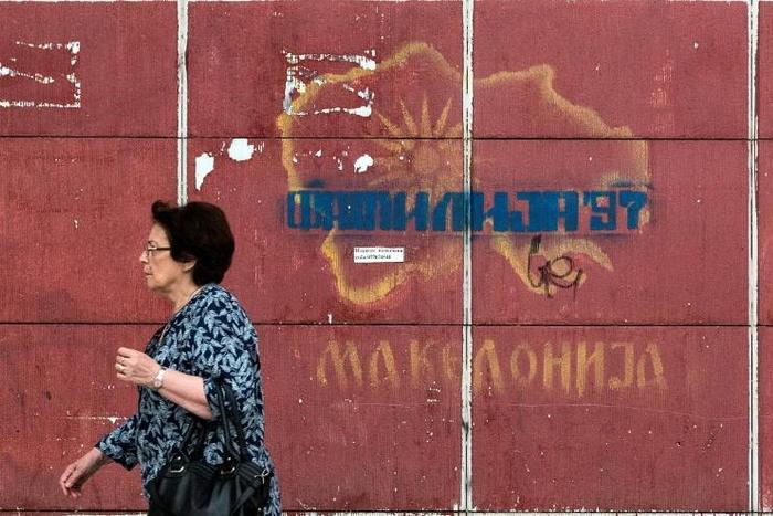 A woman passes a graffiti-strewn map in Skopje as Greek lawmakers prepare to ratify a name change for the former constituent part of Macedonia, the issue having plagued relations between the neighbours for decades