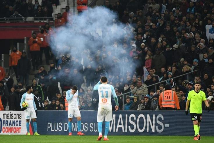 Kevin Strootman was left holding his face after a firework exploded at his feet. Jordan Amavi glared at the fans