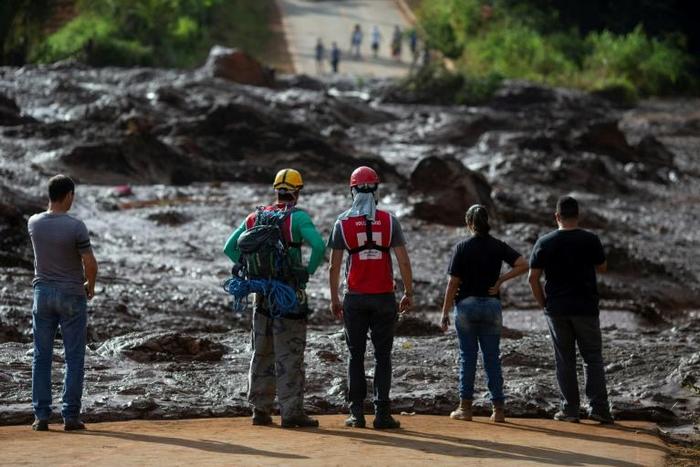 People from the community of Alfredo Torres look at the mud-hit area, a day after the deadly dam collapse