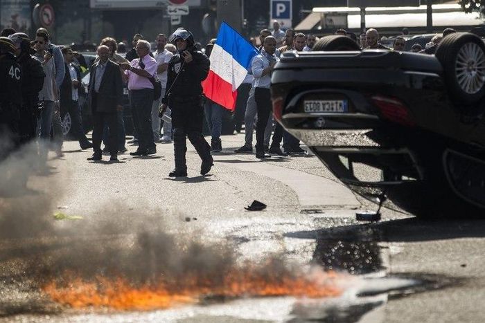 An UberPOP car was overturned by protesters who also clashed with riot police.