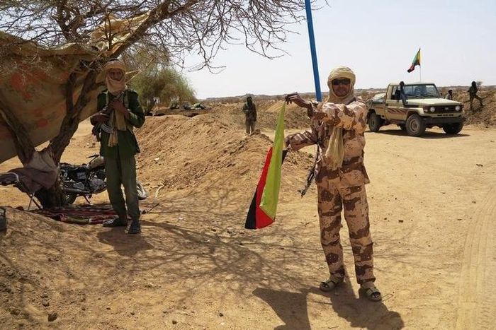 A fighter with the Tuareg separatist group MNLA (National Movement for the Liberation of Azawad) brandishes a separatist flag for the region they call Azawad outside the local regional assembly, where members of the rebel group met with the Malian army...