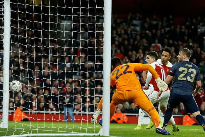 Arsenal's Gabonese striker Pierre-Emerick Aubameyang (2nd L) watches as his shot hits the empty net for Arsenal's first goal during the English FA Cup fourth round football match between Arsenal and Manchester United at the Emirates Stadium in London o...