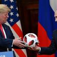 Russia's President Vladimir Putin (R) offers a ball of the 2018 football World Cup to US President Donald Trump after their meeting in Helsinki on July 16, 2018