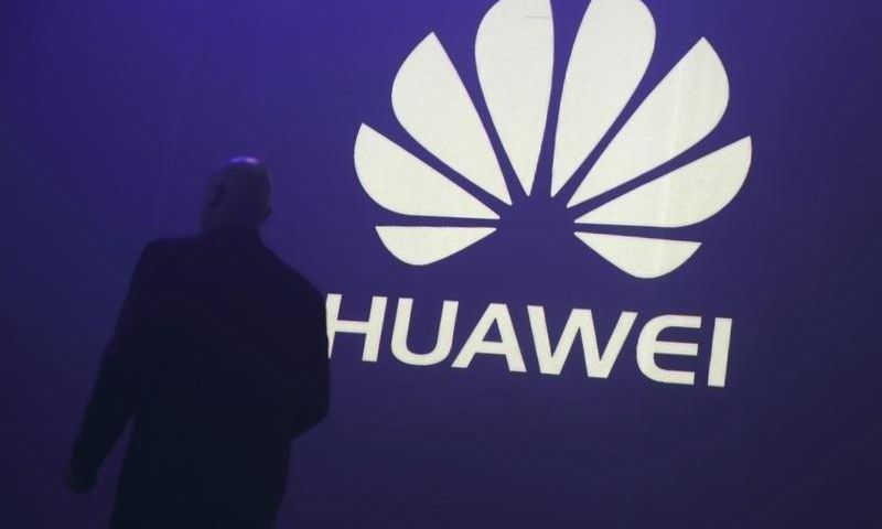 A man walks past a logo during the presentation the Huawei's new smartphone, the Ascend P7, launched by China's Huawei Technologies in Paris, May 7, 2014. REUTERS/Philippe Wojazer/Files