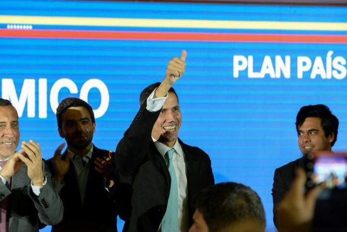 Venezuela's opposition leader and self-proclaimed "acting president" Juan Guaido (C) gives the thumbs-up as he prepares to present his "rescue plan" for the country