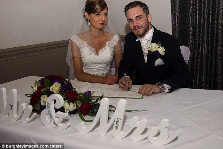 The couple pose for the camera while signing the wedding register 