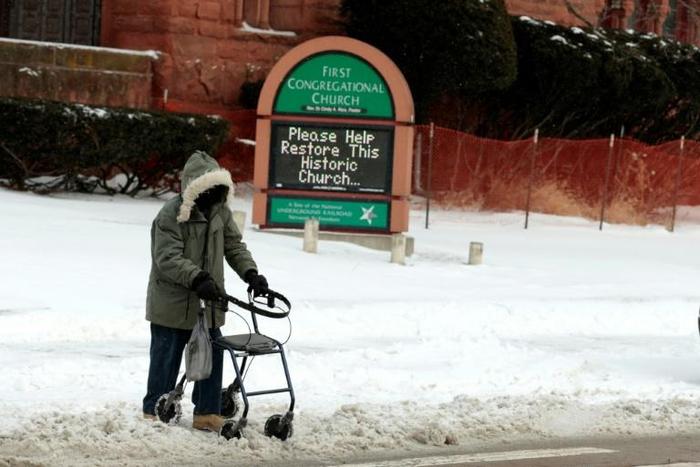 A person with a walker crosses Canfield Avenue in Detroit, Michigan