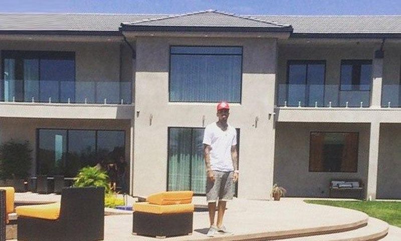 Chris Brown standing in front of his new home