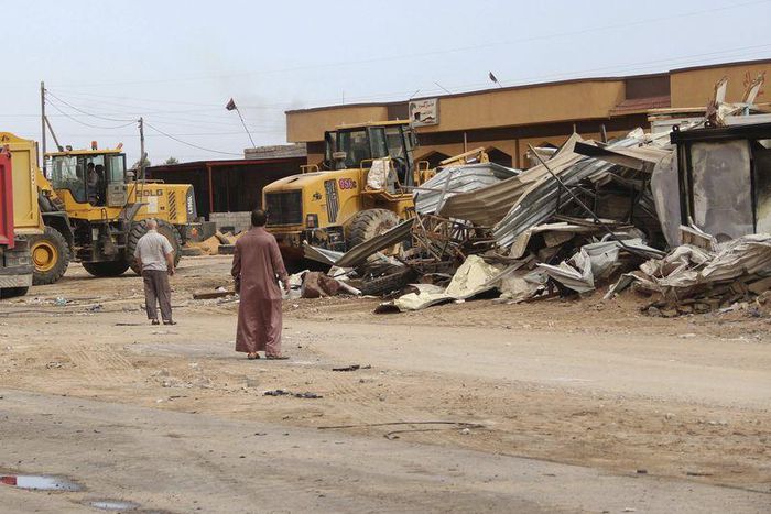 Men watch as bulldozers remove debris in front of a damaged building after a suicide car bomber blew himself up at a checkpoint in Dafniya outside Mistrata, Libya May 31, 2015. REUTERS/Stringer
