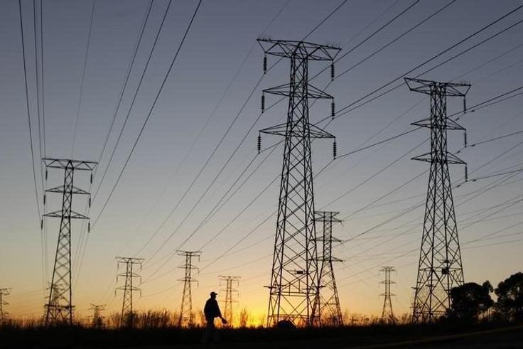 A man walks past electricity pylons as he returns from work in Soweto, outside Johannesburg May 15, 2012. REUTERS/Siphiwe Sibeko