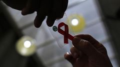 A nurse (L) hands out a red ribbon to a woman, to mark World Aids Day, at the entrance of Emilio Ribas Hospital, in Sao Paulo December 1, 2014. REUTERS/Nacho Doce