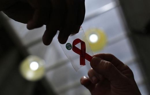 A nurse (L) hands out a red ribbon to a woman, to mark World Aids Day, at the entrance of Emilio Ribas Hospital, in Sao Paulo December 1, 2014. REUTERS/Nacho Doce