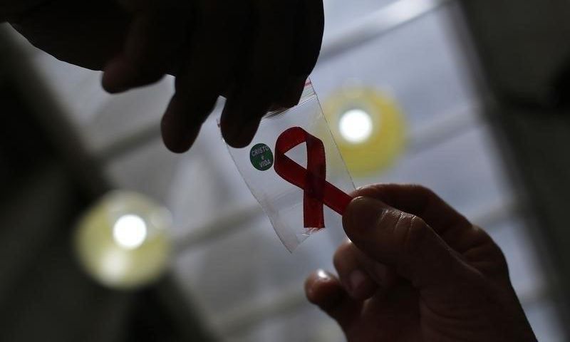 A nurse (L) hands out a red ribbon to a woman, to mark World Aids Day, at the entrance of Emilio Ribas Hospital, in Sao Paulo December 1, 2014. REUTERS/Nacho Doce