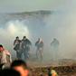 Palestinian protesters run through tear gas fumes during clashes with Israeli forces during a demonstration along the border with Israel east of Gaza City on January 11, 2019