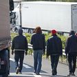 Migrants walk near trucks blocked on a road which leads to the Channel Tunnel terminal in Coquelles near Calais, northern France, July 1, 2015.    REUTERS/Vincent Kessler