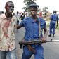 A riot policeman escorts an injured protester who was hit during clashes with riot police against the decision to allow President Pierre Nkurunziza to run for the country's third term presidency seat.