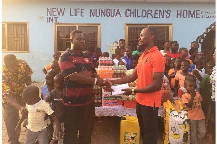 David Accam representing the items to the manager of the children's home